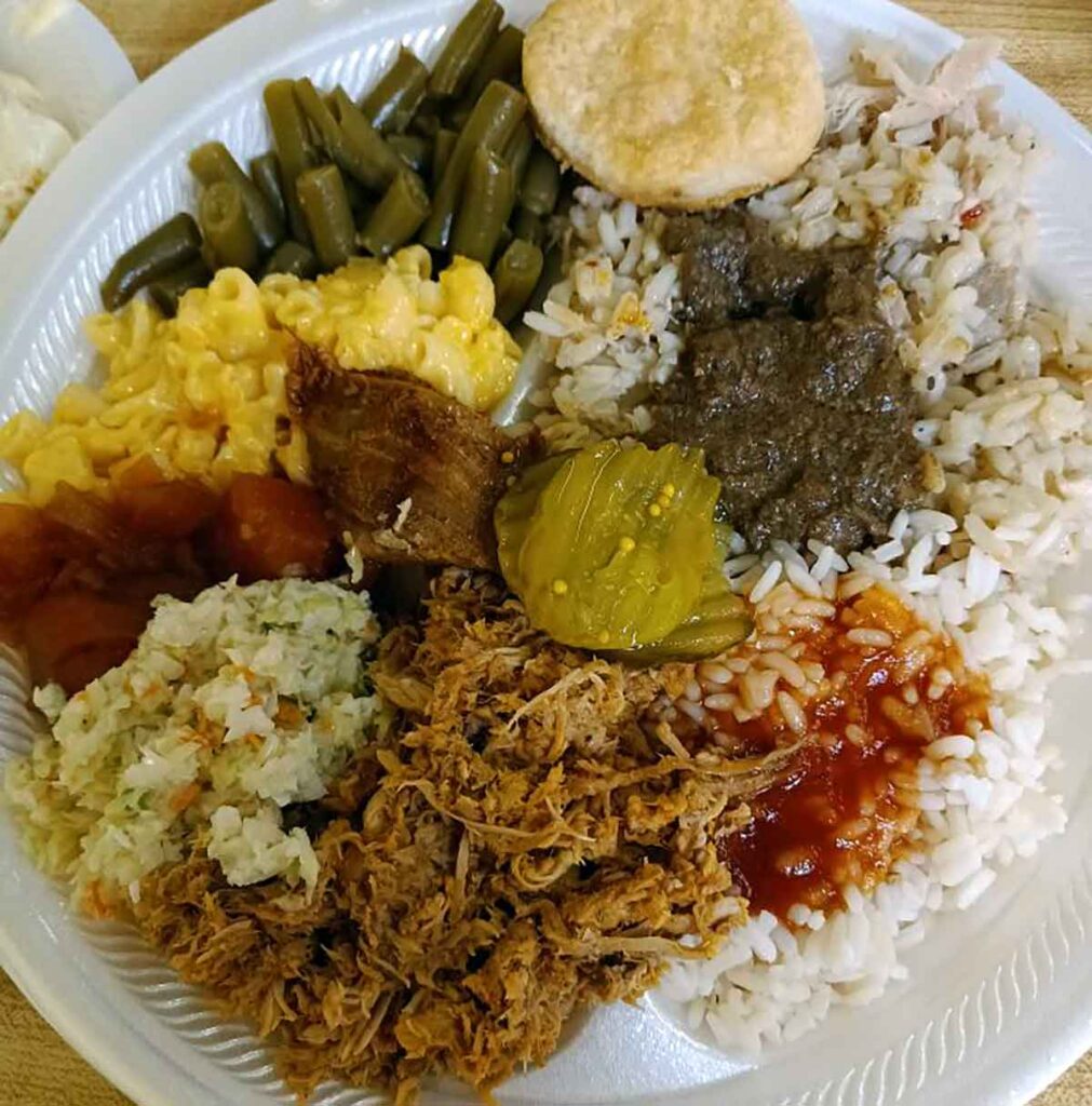 BBQ plate filled with BBQ and sides, including liver hash and red gravy over rice..