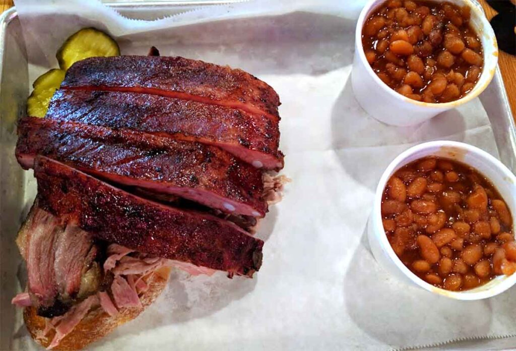 Several ribs on tray with two cups of baked beans