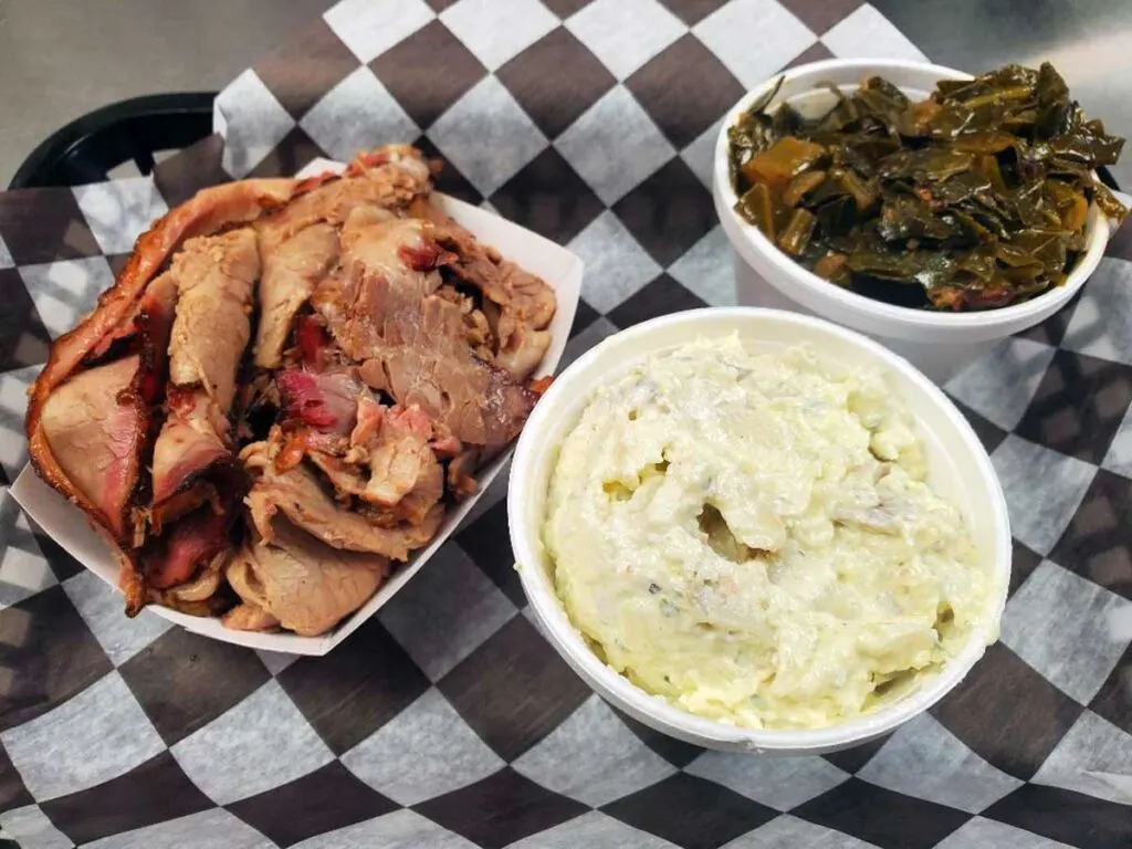 Sliced brisket with potato salad and collards.