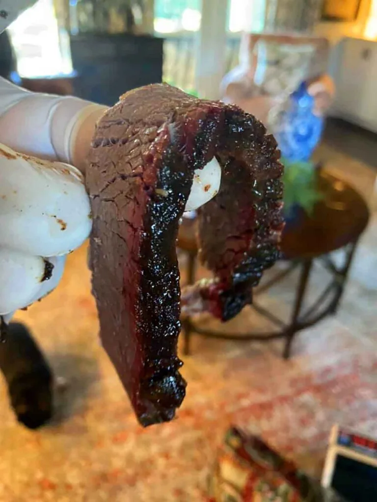 Slice of brisket hanging loosely over a finger.
