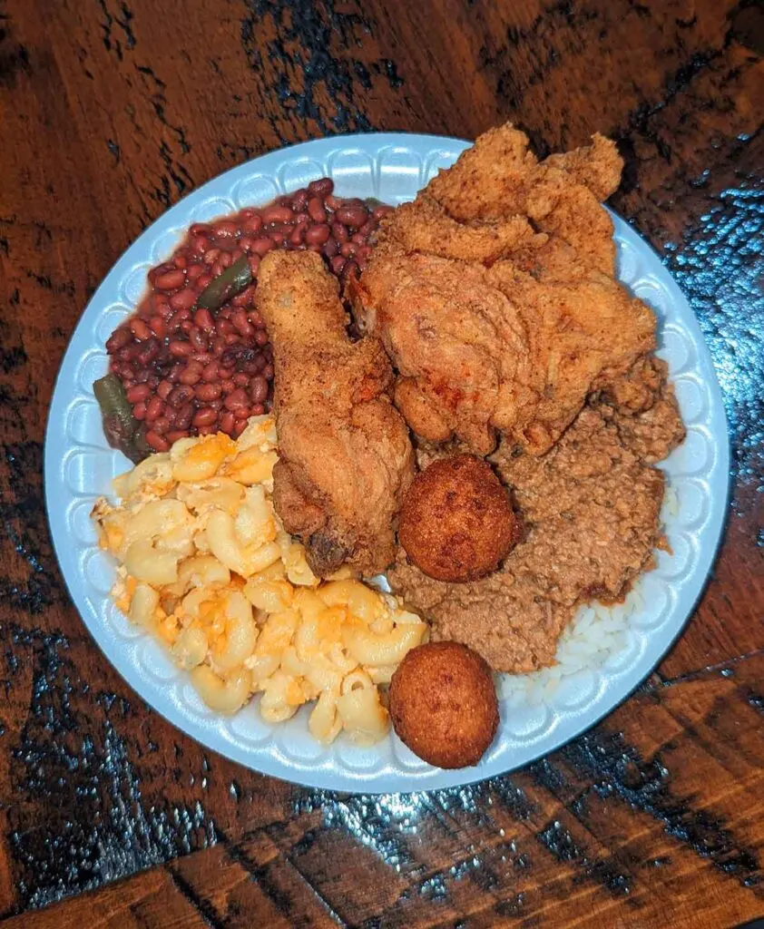 Fried chicken plate with beans, hash and rice, Mac and cheese, and hush puppies.