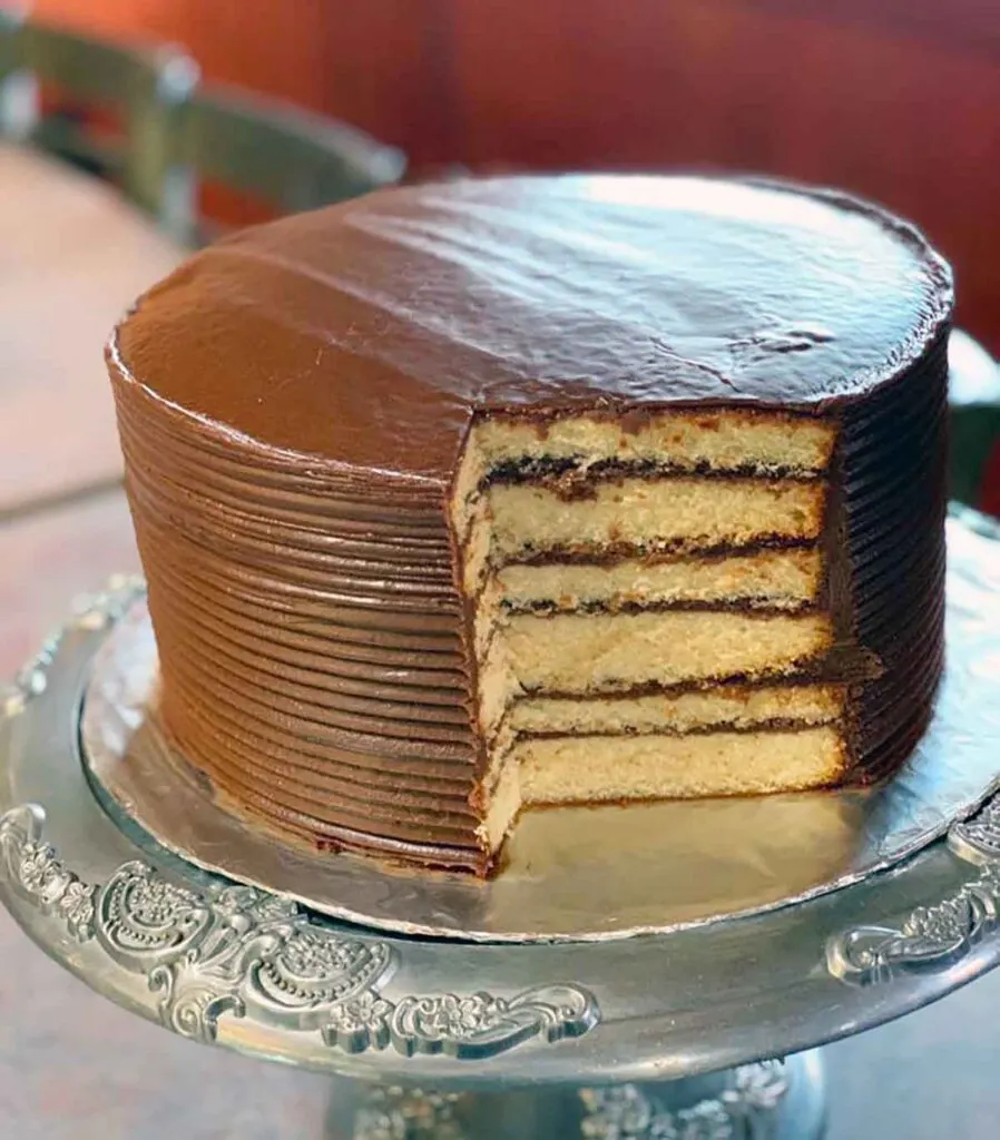 Chocolate layer cake on pedestal with slice cut away showing interior
