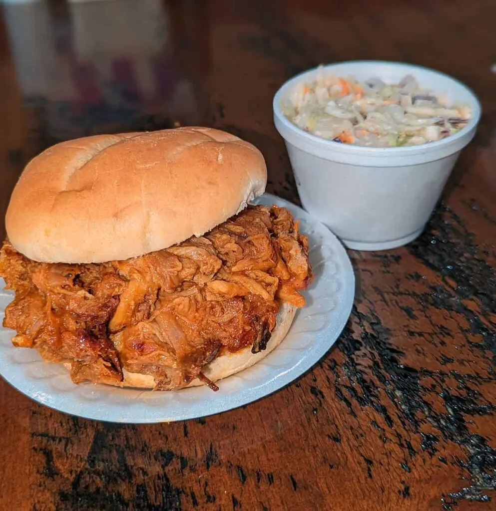 Barbecue sandwich piled high with a side of slaw.