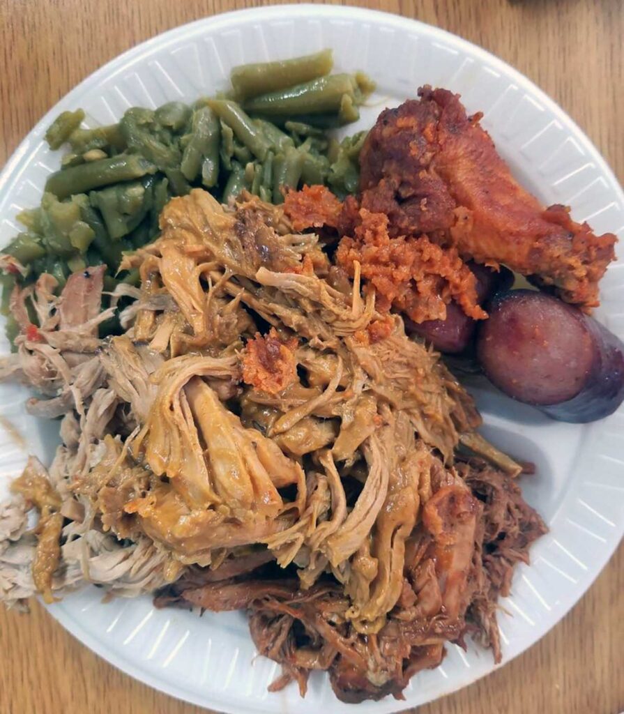BBQ piled high on plate with sausage, chicken, and green beans