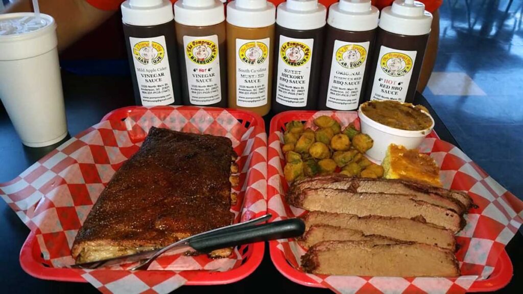 One tray of ribs, one of brisket and sides with bottles of Pompous Pig sauces behind