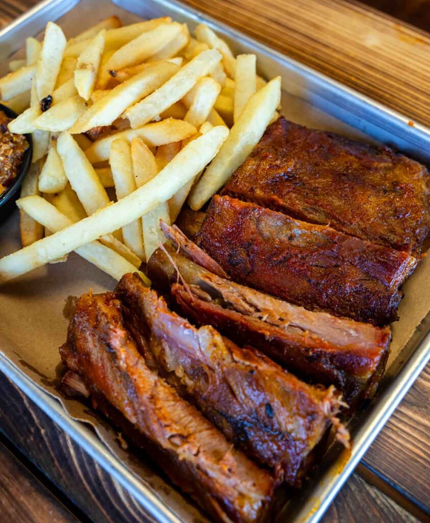 Ribs and fries on metal tray.