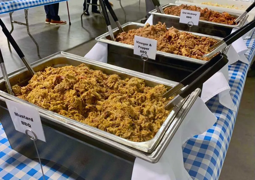 Three aluminum trays of barbecue, each with a different sauce