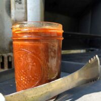 Gates and Sons BBQ Sauce in Mason jar on side of grill