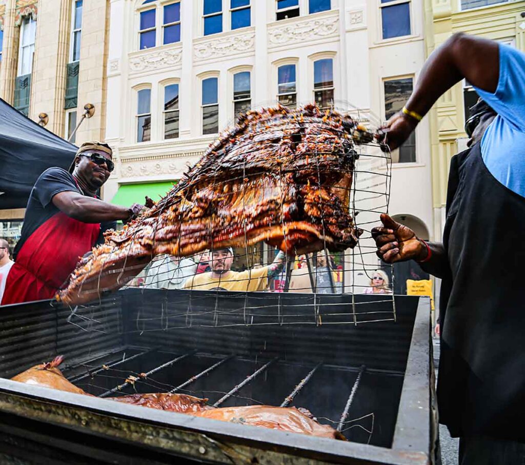 Rodney Scott flipping a whole hog as Chef Sean Brock watches from behind