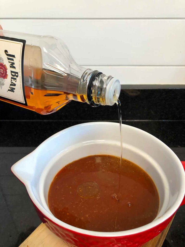 Pouring Jim Beam bourbon into Mojo sauce.