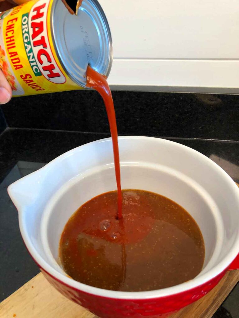 Pouring Hatch red enchilada sauce into Mojo sauce.