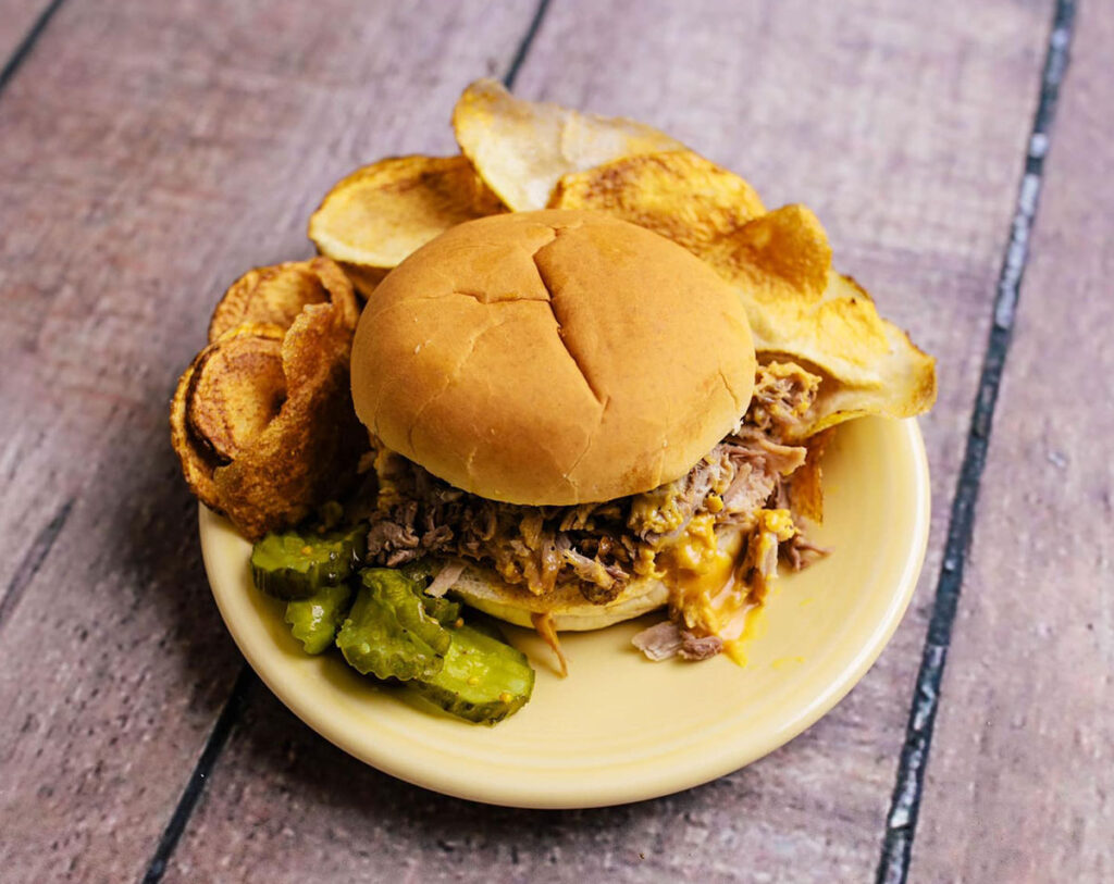 Dukes BBQ sandwich plate with chips and pickles.