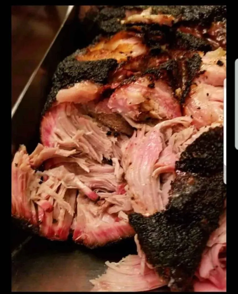 Closeup of pulled pork with dark "bark" on exterior.