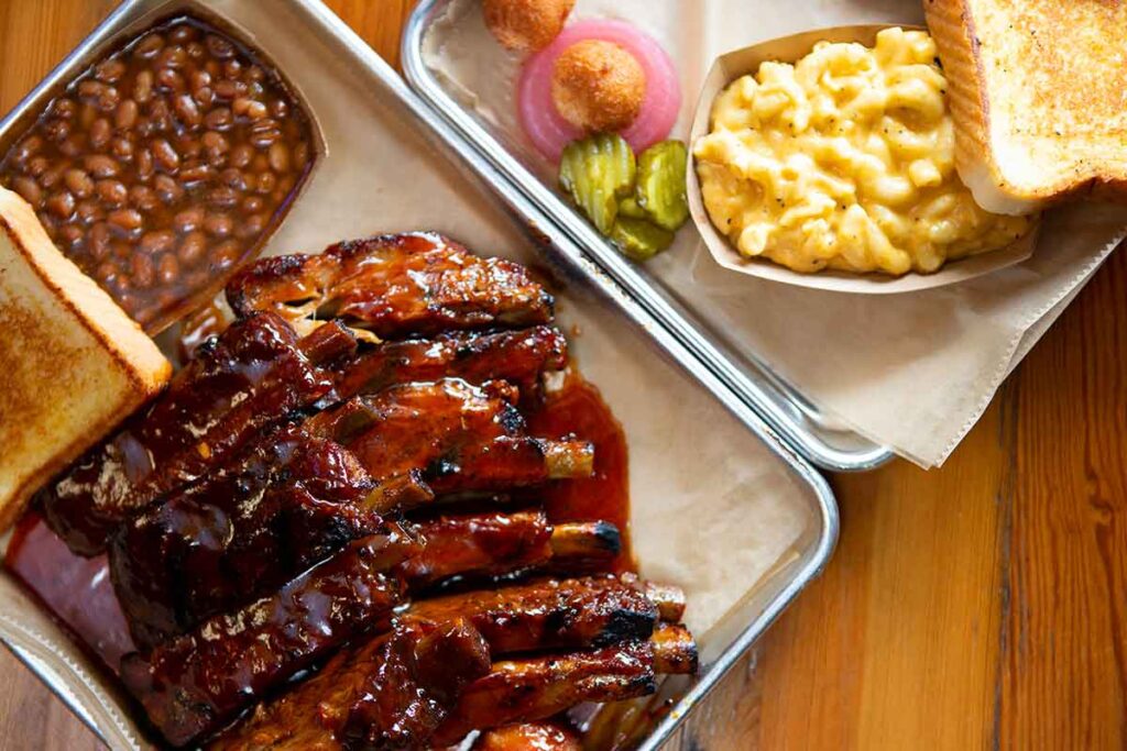 Ribs with baked beans and Mac n cheese on trays.