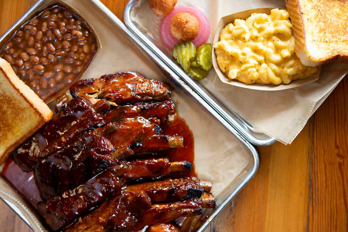 Ribs with baked beans and Mac n cheese on trays.