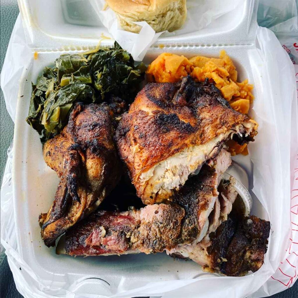 Takeout tray of chicken, ribs, collards, and sweet potatoes.