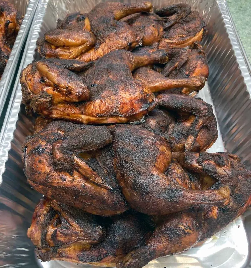 A foil pan full of barbecued chicken halves.