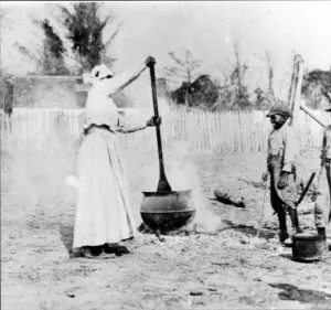 Black woman stirring SC BBQ Hash in kettle 