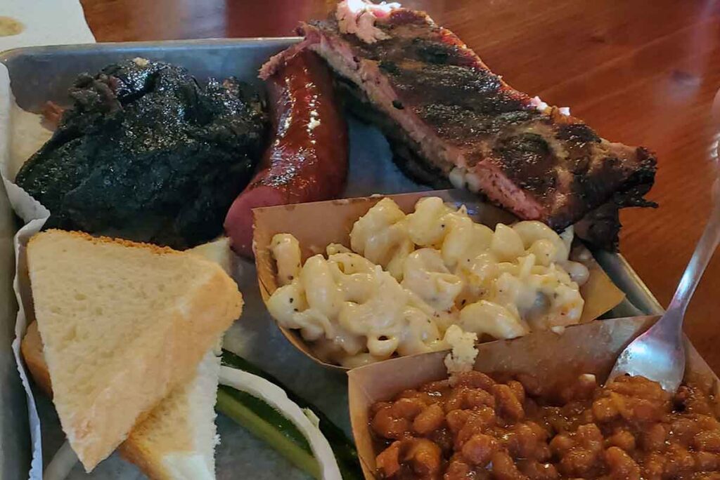 Three meats, mac, and beans with bread and pickles.