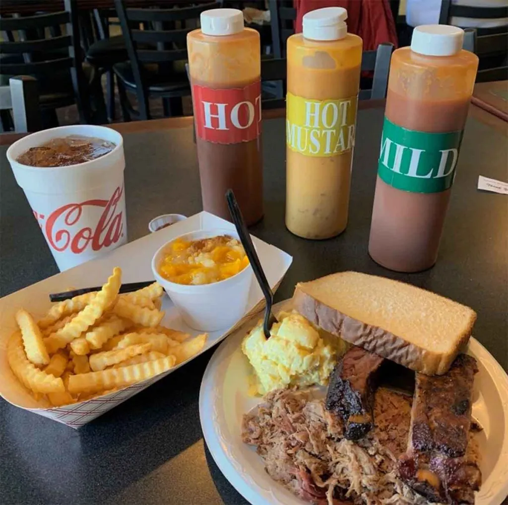 Table with three sauces, drink, fries, ribs, BBQ, and more