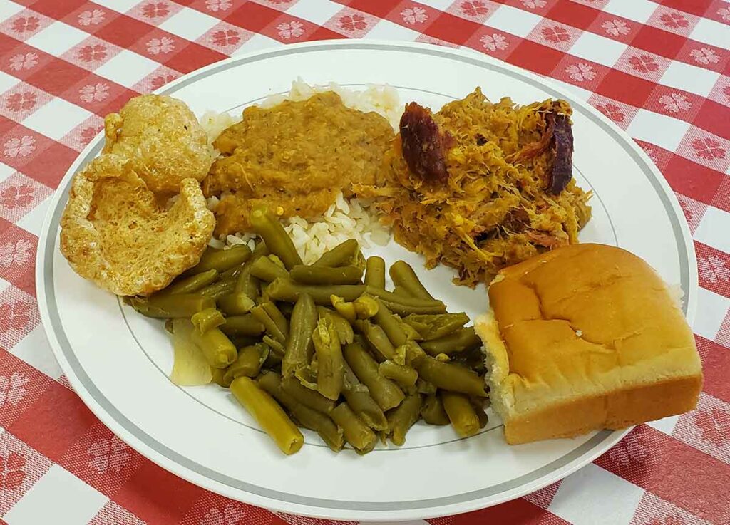BBQ plate with hash and rice, skins, green beans and a dinner roll.
