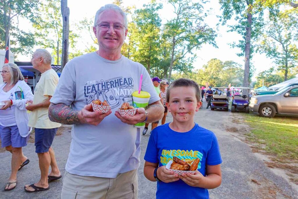 A father (or grandfather?) and son holding samples of barbecue during the Griller's Cup.