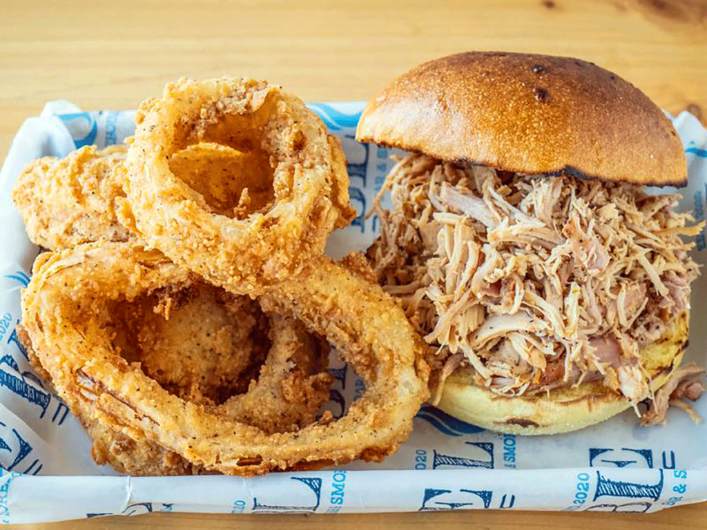 Pulled chicken sandwich with onion rings.