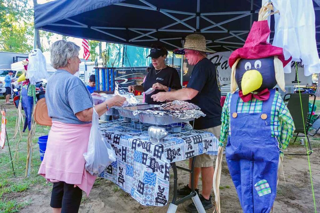 Two competitors from a cook team serve samples to a Griller's Cup attendee.