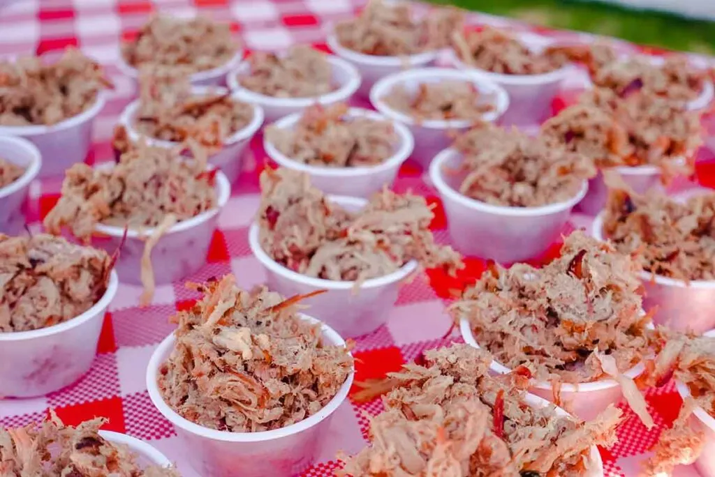 Cups of barbecue samples on gingham tablecloth.