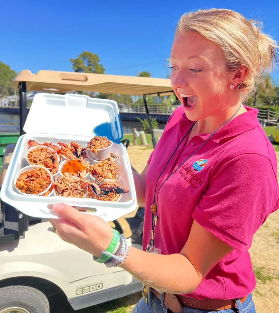 Lakewood Campground employee holding a styrofoam container which is full of sample cups of barbecue.