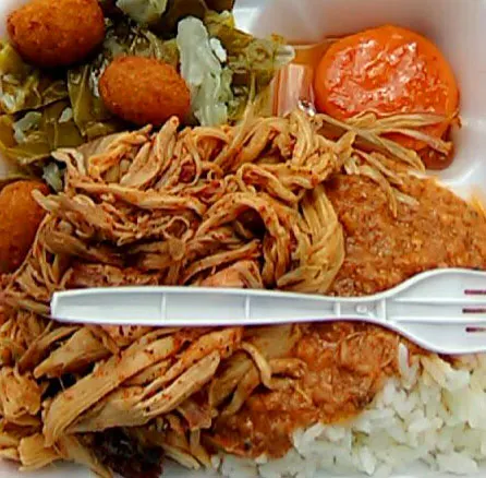 BBQ plate from McCabe's with stewed tomato, collards, hush puppies, hash and rice, and pulled pork with plastic fork on top.