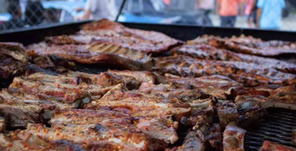 Several racks of ribs on the grill.