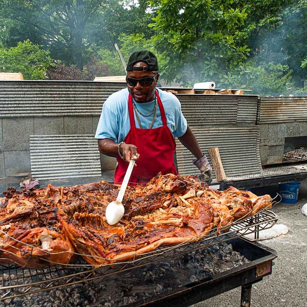 Rodney Scott spooning open a whole hog for sauce to absorb into the meat.