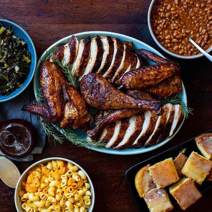 Rodney Scott's Smoked Turkey cut up on platter surrounded with various side dishes in bowls.