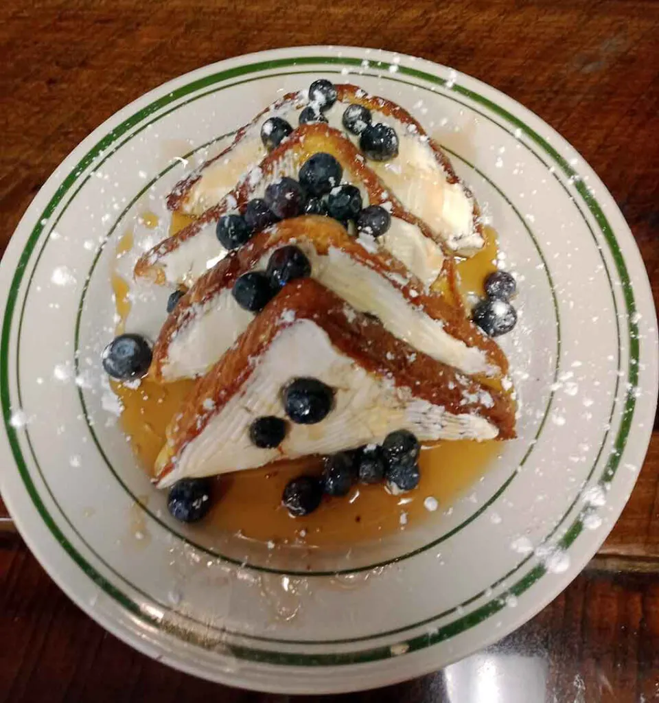 French toast on plate with blueberries and syrup