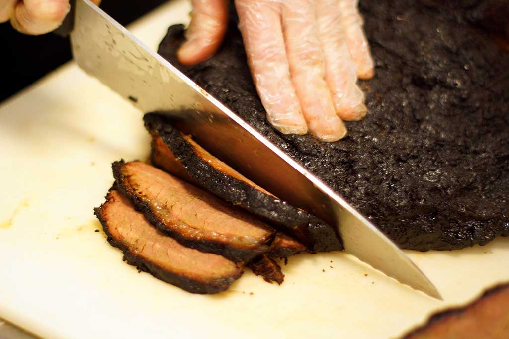 Hands carving a brisket