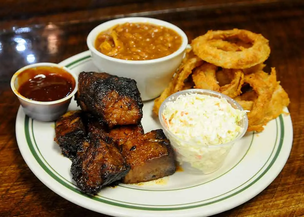 Burnt ends, baked beans, slaw and onion rings on plate