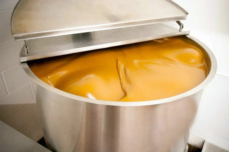 Large stainless steel vat of Bessinger's BBQ sauce swirling.