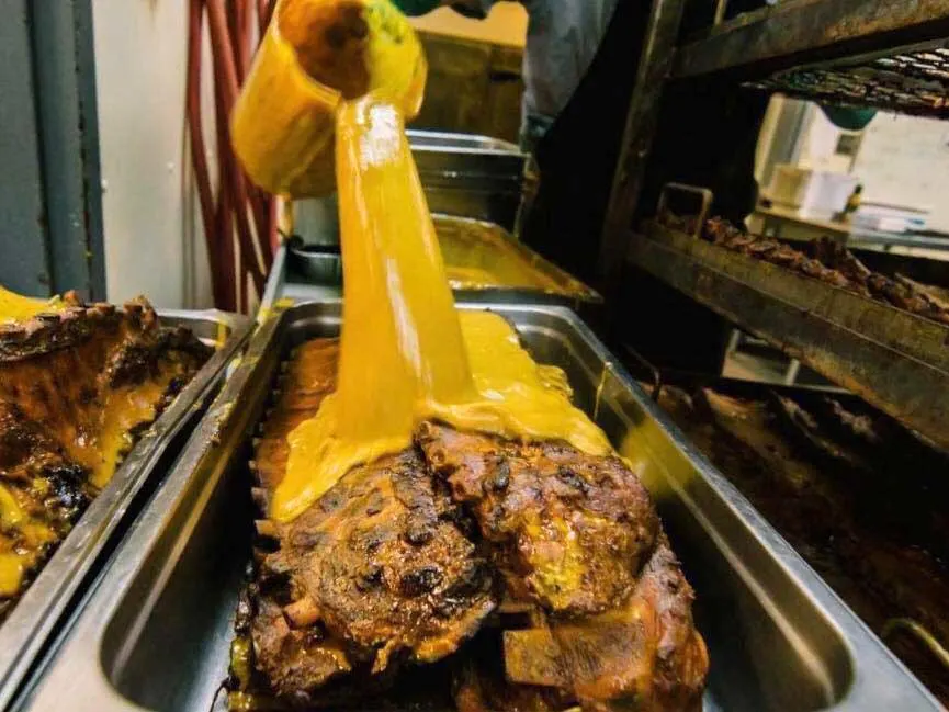 Maurice Bessinger's BBQ sauce poured over a pan of whole spareribs.