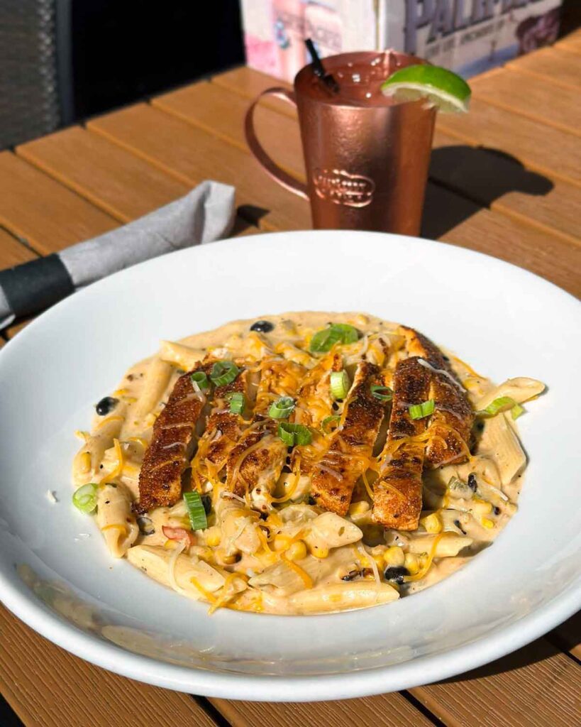 Plate of blackened chicken on top of creamy pasta.
