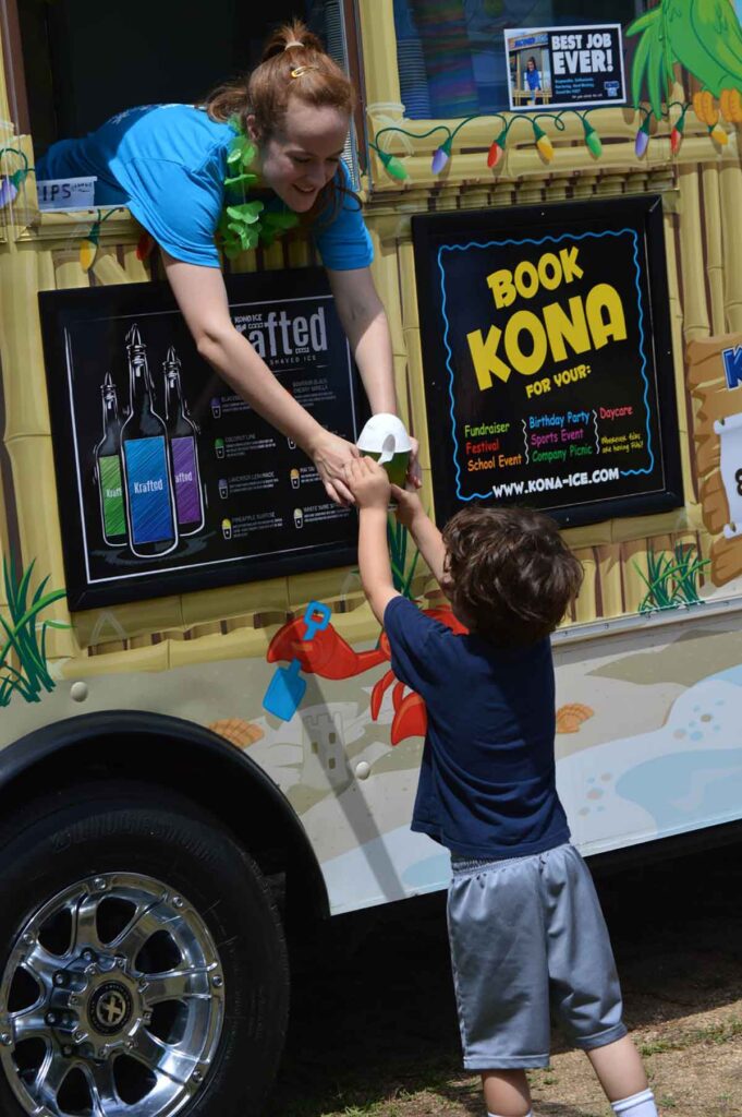 Vendor handing a snow cone to a little kid at the Camden BBQ Fest
