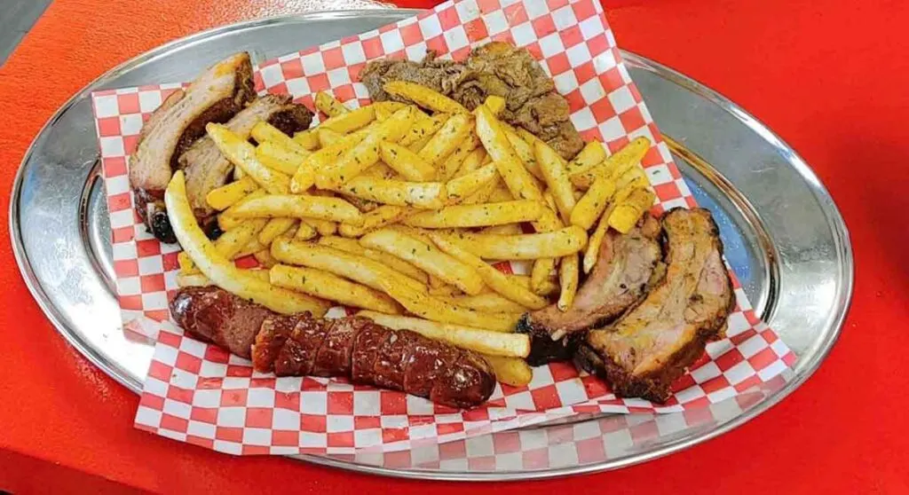 BBQ, ribs, sausage, and fries on silver platter