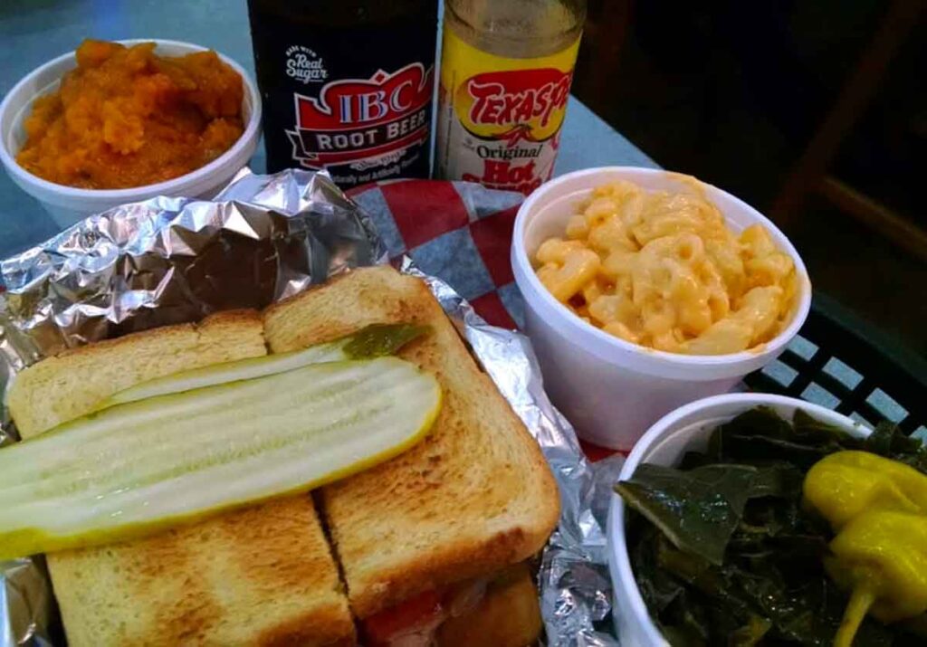 Pulled pork sandwich with Mac n Cheese, pickle, collards, and more.