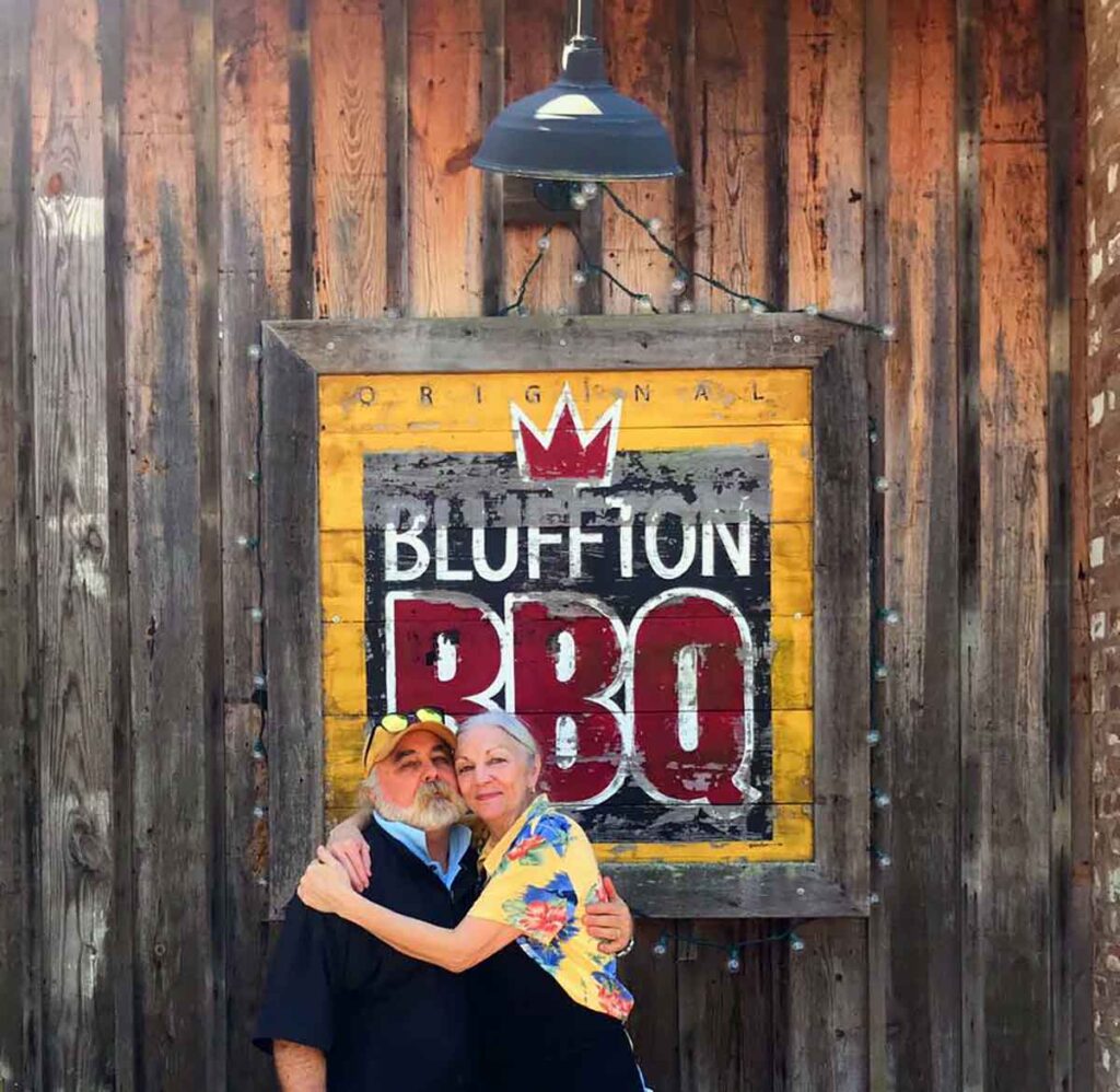 Ted and Donna Huffman, owners, standing in front of Bluffton BBQ sign on side of building