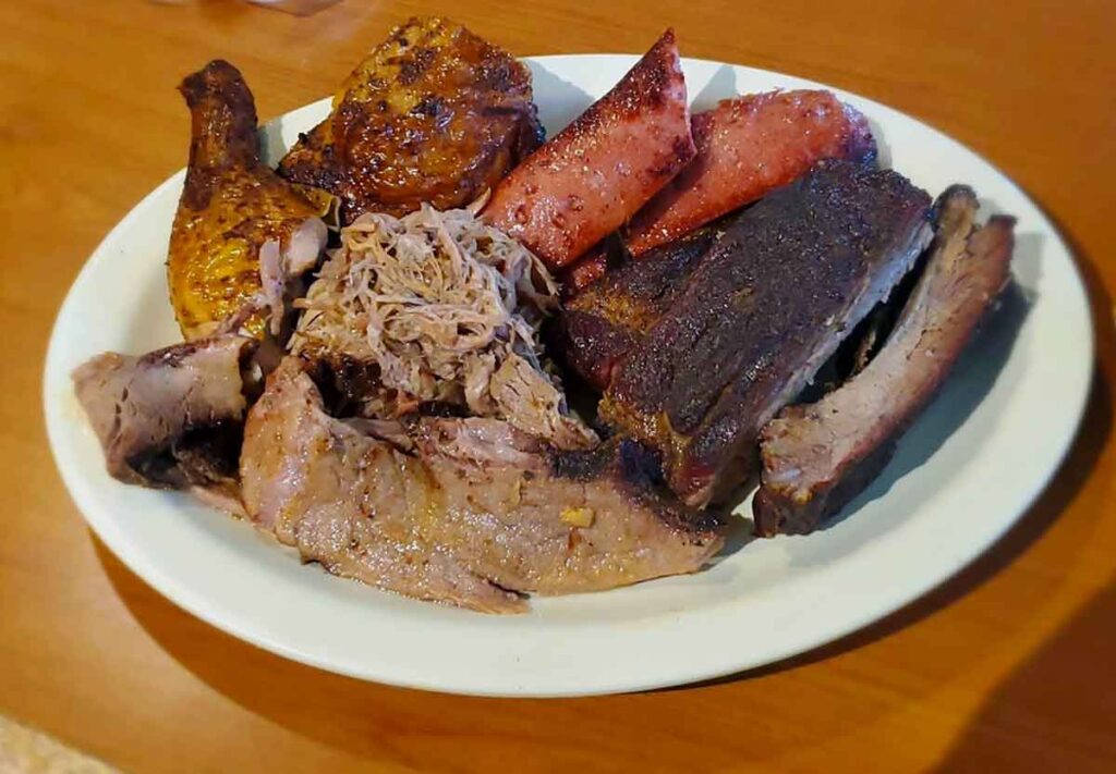 Meats sampler platter with brisket, ribs, chicken, pulled pork, and sausage.