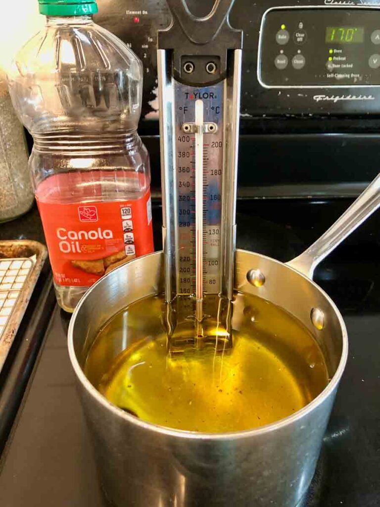 Pot with thermometer full of canola oil.