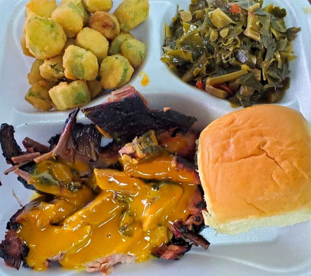 Pulled pork with sauce, fried okra, collards and a dinner roll.