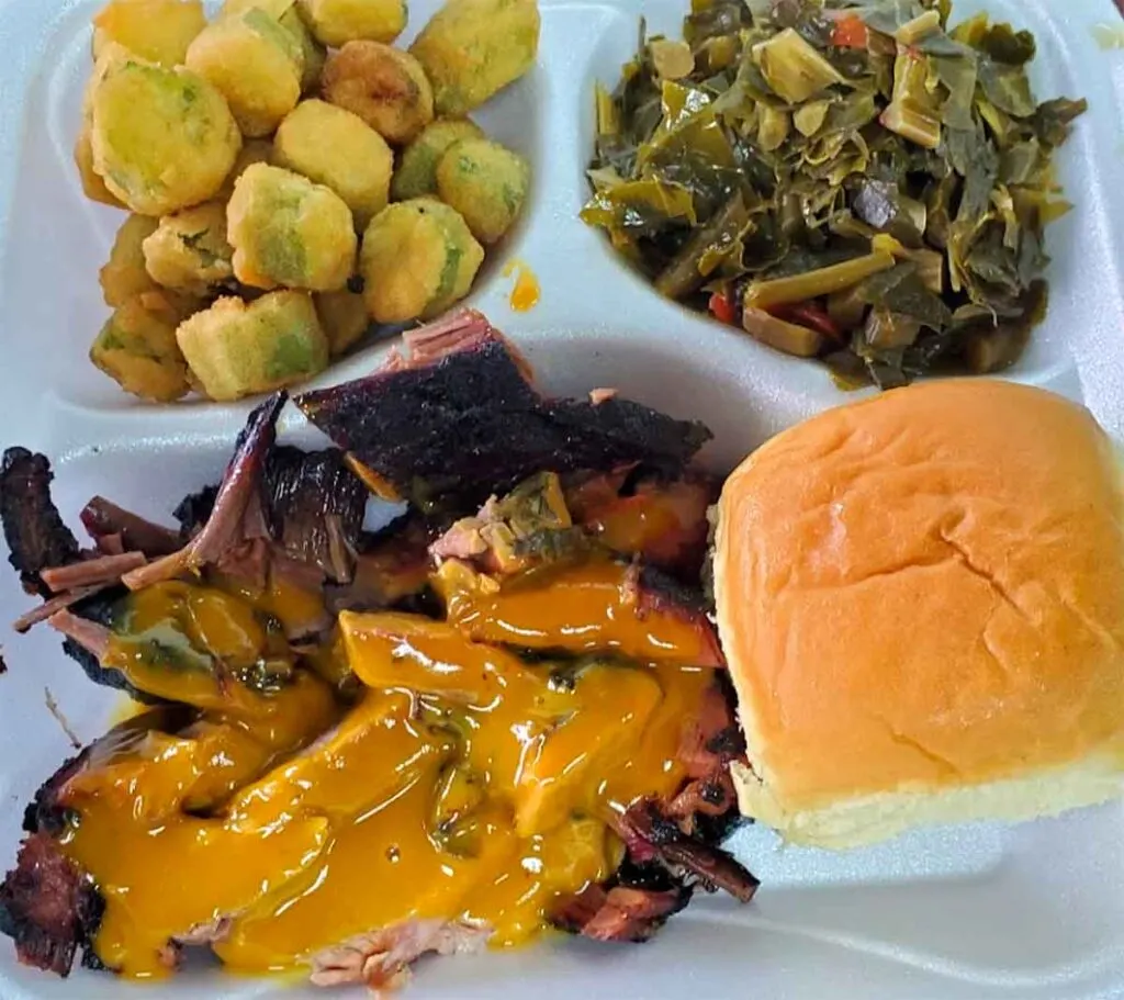 Pulled pork with sauce, fried okra, collards and a dinner roll.