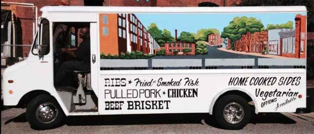 Broadside of Wholy Smoke's food truck with mural and menu options on side.