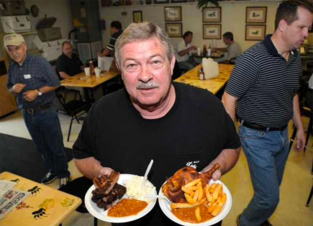 Joe Crook, founder of Pig Out BBQ, holding two plates of barbecue